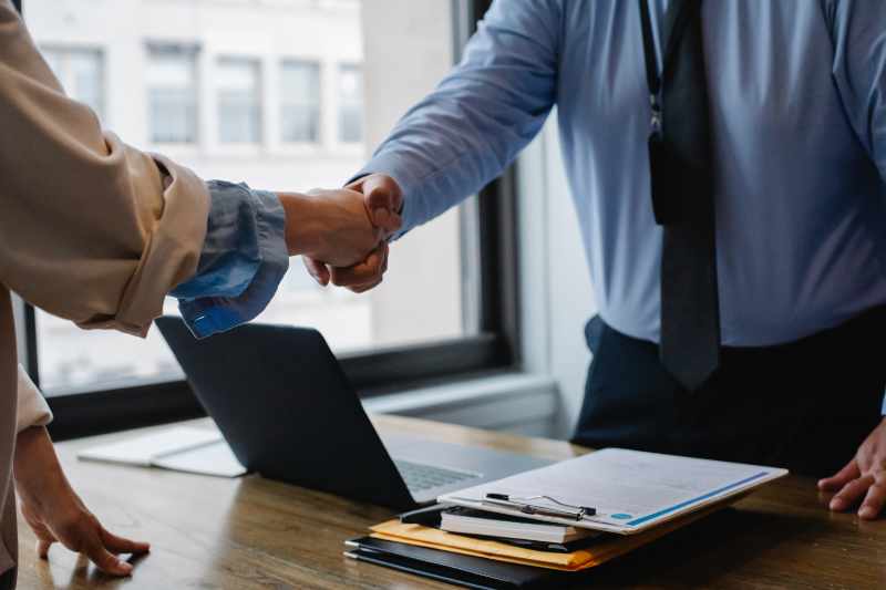 Professionals shaking hands over desk