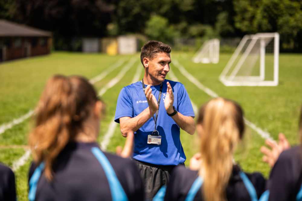 Sports teacher on field with students